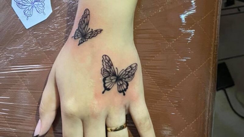 FLOR BORBOLETA NA MÃO – tatuagem de flor e borboleta na mão. 